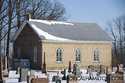Side Of The White Brick Church With Cemetery Infront